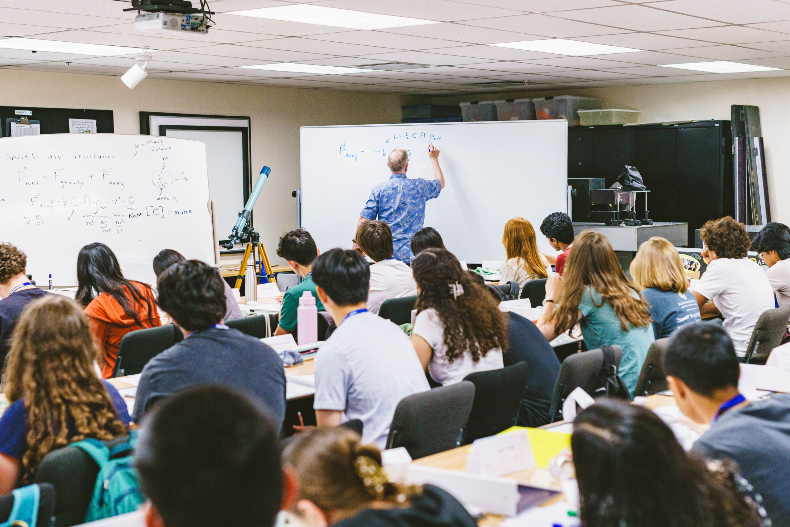 Students immerse themselves in campus life as they sit attentively in a classroom, eyes glued to the teacher who elegantly pens equations on the whiteboard.